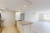 Located at 175 James Street in Worcester, MA, this thoughtfully designed single-floor residence offers four bedrooms and three bathrooms with a clean, contemporary aesthetic throughout. The open-concept kitchen and living area serves as the heart of the home, anchored by a central island topped with granite countertops, white shaker cabinetry, pendant lighting, and a stainless steel sink. The kitchen flows seamlessly into the spacious living area, all unified by light-toned hardwood flooring that extends throughout the entire unit. A ductless mini-split system provides efficient climate control across multiple rooms. The generously sized primary bedroom offers a walk-in closet with built-in wire shelving, providing ample storage. The additional three bedrooms are bright and well-proportioned, each benefiting from large windows that invite natural light and views of the surrounding greenery. Two closets serve the household's storage needs. A dedicated in-unit laundry area houses a stacked washer and dryer, adding everyday convenience. The neutral, light color palette across all rooms creates a calm, cohesive atmosphere, while the modern finishes and clean lines give the space a fresh, move-in-ready appeal.