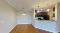 Located at 4101 W Huntington Dr in Rogers, Arkansas, this single-floor unit offers a well-designed layout with a cohesive blend of warm finishes and functional spaces throughout. The open living and dining area is anchored by rich hardwood-style flooring, crown molding, and pendant lighting, creating an inviting atmosphere. Large windows allow generous natural light to fill the space, complemented by a ceiling fan for added comfort. The kitchen features dark espresso cabinetry, granite-style countertops, a breakfast bar peninsula, and black appliances including a refrigerator, range, and microwave. A hallway off the kitchen provides access to additional rooms and storage. The bedrooms are carpeted for comfort, each offering natural light via blinded windows. One bedroom includes a walk-in closet with built-in shelving and hanging rods. The two bathrooms are finished consistently with dark vanity cabinetry, granite-style countertops, large mirrors with lighted fixtures, and neutral tile flooring. A dedicated laundry area includes a full-size washer and dryer. Neutral wall tones and white trim work throughout the unit contribute to a clean, move-in-ready aesthetic.