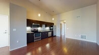 Located at 1685 E 118th St in Cleveland, Ohio, this single-floor residence showcases a thoughtfully designed open layout with striking architectural details throughout. The living and kitchen areas are unified by rich hardwood flooring and dramatic vaulted ceilings that amplify the sense of space and openness. Clerestory windows allow natural light to pour in along the upper walls, enhancing the airy atmosphere.

The kitchen is a standout feature, offering dark espresso cabinetry, granite countertops, and a full suite of stainless steel appliances including a range, microwave, dishwasher, and refrigerator. Stylish pendant lighting hangs above, adding a modern touch. The open-concept design connects the kitchen seamlessly to the spacious living area, which includes access to an outdoor space through glass doors.

The bedrooms are carpeted for comfort and warmth, each featuring windows that bring in natural light and views of the surroundings. The bathroom is well-appointed with a wide granite-topped vanity, dark wood cabinetry, and tile flooring, complemented by a well-lit mirror and additional storage. The overall design balances contemporary finishes with a clean, neutral palette, creating a welcoming and functional living environment.