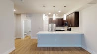 This well-appointed 3-floor residence combines contemporary design with practical functionality throughout its thoughtfully laid-out spaces. The open-concept main living area serves as the heart of the home, where the kitchen flows seamlessly into the living room. The kitchen is outfitted with rich dark cabinetry, a subway tile backsplash, stainless steel appliances including a refrigerator, microwave, and range, and a generous island with a crisp white quartz countertop, undermount sink, and stylish pendant lighting overhead. The adjacent living area features warm hardwood-style flooring, a ceiling fan, and large windows and glass doors that invite abundant natural light and outdoor views. Bedrooms offer comfortable retreats, with plush carpeting, ceiling fans, and windows providing natural light; one bedroom features hardwood-style flooring. Spacious walk-in closets with dual hanging rods and shelving provide ample storage. The bathrooms are finished with dark wood vanities, white quartz countertops, large mirrors, and a tiled tub-shower combination. A convenient half-bath is also present. The ground floor includes a well-sized attached garage with an automatic opener, providing secure parking and additional storage capacity. Clean neutral tones and consistent finishes lend a cohesive, modern ambiance throughout the entire space.