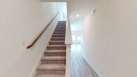 This two-story home is designed with a clean, contemporary aesthetic throughout, combining practical functionality with bright, neutral interiors. The main level features wood-look plank flooring that extends through the kitchen, hallways, laundry room, and bathroom, creating a cohesive and easy-to-maintain foundation. The kitchen is a well-appointed space equipped with white shaker-style cabinetry, granite countertops with subtle veining, stainless steel appliances including a range, over-the-range microwave, dishwasher, and refrigerator, as well as a central island with an undermount sink. A dedicated laundry room on the main level includes built-in shelving, appliance hookups, and wood-look flooring. A full bathroom on this level features a tub-shower combination with subway tile surround, a single-sink vanity, and wood-look flooring. The staircase, lined with carpet and a wooden handrail, connects the levels and opens to a hallway leading to the upper floor. Upstairs, generously sized bedrooms are finished with plush carpet and receive natural light through windows with exterior views. A spacious walk-in closet with wrap-around hanging rods and carpet provides ample storage. The overall ambiance is light, airy, and move-in ready.