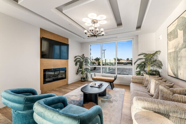 Elegante sala de estar con decoración moderna, con lujosos sillones, un sofá contemporáneo, una elegante chimenea y grandes ventanales. - Triton Cay - Daytona Apartments