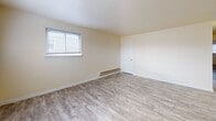 Located at 1127 Ward St in Chester, Pennsylvania, this single-floor unit offers a clean, updated interior with a straightforward and functional layout. Throughout the space, neutral cream-toned walls and durable wood-look vinyl plank flooring create a bright, cohesive aesthetic that carries from room to room.

The living area is generously proportioned, benefiting from multiple windows that invite natural light and create an open, airy feel. Each bedroom is well-sized, featuring individual windows with exterior views, baseboard heating, and ample wall space. One bedroom includes a built-in closet with paneled doors alongside an electrical panel, adding to its practicality.

The kitchen is a functional highlight, equipped with warm wood cabinetry, granite-style countertops, a stainless steel sink, and a stainless steel electric range. A tiled backsplash in a soft blue-grey tone adds a subtle design touch, complementing the overall neutral palette.

The bathroom features a clean, white tub-shower surround with brushed nickel hardware, including a towel bar and toilet paper holder, maintaining a simple and tidy finish. The dollhouse view reveals a compact yet efficient floor plan that connects all areas seamlessly, making this a well-organized and move-in-ready space.