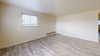 Located at 1127 Ward St in Chester, Pennsylvania, this single-floor unit offers a clean, updated interior with a straightforward and functional layout. Throughout the space, neutral cream-toned walls and durable wood-look vinyl plank flooring create a bright, cohesive aesthetic that carries from room to room.

The living area is generously proportioned, benefiting from multiple windows that invite natural light and create an open, airy feel. Each bedroom is well-sized, featuring individual windows with exterior views, baseboard heating, and ample wall space. One bedroom includes a built-in closet with paneled doors alongside an electrical panel, adding to its practicality.

The kitchen is a functional highlight, equipped with warm wood cabinetry, granite-style countertops, a stainless steel sink, and a stainless steel electric range. A tiled backsplash in a soft blue-grey tone adds a subtle design touch, complementing the overall neutral palette.

The bathroom features a clean, white tub-shower surround with brushed nickel hardware, including a towel bar and toilet paper holder, maintaining a simple and tidy finish. The dollhouse view reveals a compact yet efficient floor plan that connects all areas seamlessly, making this a well-organized and move-in-ready space.