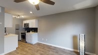 This 1-bedroom, 1-bathroom unit offers a thoughtfully designed single-floor layout that maximizes functionality and style. The open living area features warm wood-look flooring, neutral gray walls, and a ceiling fan with integrated lighting, creating a bright and welcoming atmosphere. A large window with blinds allows natural light to fill the space, enhancing its airy feel.

The galley-style kitchen is a standout feature, showcasing white shaker cabinetry with brushed nickel hardware, light quartz countertops, and a striking dark subway tile backsplash. Stainless steel appliances — including a refrigerator, electric range, built-in microwave, and dishwasher — complete this sleek and efficient culinary space. Track lighting overhead ensures excellent visibility throughout the kitchen.

The bedroom is a comfortable retreat, equipped with its own ceiling fan, wood-look flooring, and a window that invites natural light. The full bathroom is finished with clean, contemporary fixtures, a white vanity with storage, wood-look tile flooring, and a tub-shower combination with tile surround. Consistent use of neutral tones and modern hardware throughout ties the entire unit together, presenting a cohesive and move-in-ready living space.