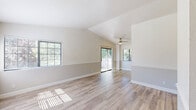 Located at 1164 E Perrin Ave in Fresno, California, this single-story, three-bedroom, two-bathroom home offers a well-organized layout with a clean, neutral aesthetic throughout. The kitchen and living room share an open-concept design, with the kitchen featuring white cabinetry, rich dark granite countertops, stainless steel appliances including a refrigerator and range, and light wood-style flooring that extends seamlessly into the adjacent living area. A peninsula-style counter divides the spaces, adding functionality and definition. The living area benefits from two-tone painted walls and abundant natural light streaming through large windows fitted with blinds. Two hallways connect the main living spaces to the bedrooms and bathrooms, ensuring an efficient flow. All three bedrooms are carpeted, bright, and windowed, offering comfortable natural light and outdoor views. The primary bedroom provides a generous footprint among the three. Both bathrooms feature tile flooring, white cabinetry, and granite-topped vanities. The primary bathroom includes a glass-enclosed walk-in shower, while the second bathroom offers a standard configuration. The home's consistent use of neutral tones, updated finishes, and practical layout makes for a cohesive and functional living environment.
