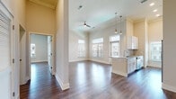 This single-floor residence offers a thoughtfully designed open-concept layout that seamlessly connects the living area to the kitchen. The main living space is characterized by soaring ceilings, crown molding, and rich hardwood-style flooring that extends throughout the entire unit. Large windows allow generous natural light to fill the space, offering views of the surrounding neighborhood. A ceiling fan adds both function and style to the living area.

The kitchen is well-equipped with white shaker-style cabinetry, granite countertops, stainless steel appliances including a refrigerator, electric range, and microwave, and a classic subway tile backsplash. Elegant pendant lighting hangs above the kitchen peninsula, which provides additional prep and seating space.

The bedrooms are generously proportioned, each featuring the same hardwood-style flooring, neutral wall tones, and ample natural light. Crown molding is present in select rooms, adding an elevated architectural detail.

The bathrooms are finished with white vanity cabinetry, granite countertops, framed mirrors, and a glass-enclosed shower with white tile surround. A hallway with a closet connects the private areas of the residence. The overall aesthetic is clean, modern, and move-in ready.
