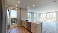 Located at 1273 Lakeside Dr in Sunnyvale, CA, this single-floor residence offers a thoughtfully designed open-concept layout with contemporary finishes throughout. Light-toned luxury vinyl plank flooring runs continuously across the living areas, complementing the neutral warm-gray walls and creating a cohesive, modern aesthetic.

The spacious living area is defined by a sweeping bank of floor-to-ceiling windows along two walls, flooding the interior with abundant natural light and offering elevated views of the surrounding tree canopy and neighborhood. Direct access to an outdoor balcony further connects the interior to the outdoors.

The kitchen is designed for both function and style, featuring white shaker cabinetry, a subway tile backsplash, stainless steel appliances including a refrigerator, range, and built-in microwave, and a generous island with a white quartz countertop and an undermount sink. Recessed lighting illuminates the space efficiently.

The bedrooms continue the light and airy theme, each featuring large windows with outdoor views and ample natural light. The primary bathroom includes a dual-sink floating vanity with white quartz countertops, a glass-enclosed shower, and wood-look flooring. A secondary bathroom offers a full tub-shower combination with clean white tile surround.
