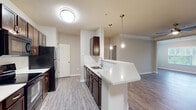 This single-floor residence in Columbus, Georgia offers a thoughtfully designed layout with a cohesive neutral color palette and wood-look flooring throughout the main living areas. The entryway provides a clean, functional transition into the home, featuring a wall-mounted thermostat and direct access to adjoining spaces.

The open-concept kitchen is a standout feature, equipped with dark espresso cabinetry, black appliances including a refrigerator, range, and microwave, and a white peninsula countertop that doubles as a breakfast bar. Pendant lighting hangs above the peninsula, adding a polished touch. The kitchen flows naturally into the dining and living areas, which are accented by crown molding and a ceiling fan, creating a comfortable, connected space.

The bedrooms are carpeted and generously sized, each offering natural light through sizable windows. One bedroom includes an ensuite bathroom and a closet, while both bathrooms feature tub-shower combos with tiled surrounds, light tile flooring, and dark vanity cabinetry. The overall design is clean and modern, with consistent finishes that lend a cohesive, move-in-ready feel throughout the home.