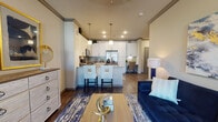 This thoughtfully designed single-floor residence showcases a seamless open-concept layout that connects the living area, dining space, and kitchen into one cohesive and inviting environment. Rich hardwood-style flooring flows throughout the main living areas, complemented by elegant crown molding that adds a refined architectural touch.

The kitchen is a standout feature, boasting crisp white shaker cabinetry extending to the ceiling, granite countertops, a subway tile backsplash, and a full suite of stainless steel appliances including a side-by-side refrigerator, range, and microwave. A central island with a deep basin sink and seating for multiple guests serves as both a functional workspace and a casual gathering spot, illuminated by stylish pendant lighting overhead.

The living room is bright and comfortable, with a large window allowing natural light to fill the space. A built-in desk area nearby provides a convenient workspace just off the main living zone.

The bedroom is a serene retreat, featuring plush carpeting, a ceiling fan, a window with natural light, and generous crown molding. Double doors open into a spacious walk-in closet with ample rod and shelf storage.

The bathroom is finished with granite countertops, an undermount sink, brushed nickel fixtures, and a soaking tub with tile surround, completing this well-appointed residence.