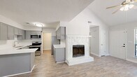Located at 60 Jane Ln in Newnan, GA, this thoughtfully designed 2-bedroom, 2-bathroom single-floor home offers a welcoming and functional layout throughout. The open living area immediately impresses with soaring vaulted ceilings and a ceiling fan, creating an airy sense of volume enhanced by natural light streaming through large windows with blinds. Wood-look luxury vinyl plank flooring runs throughout the entire home, providing a cohesive and modern aesthetic. A standout feature of the living space is the white stone-surround fireplace, which serves as a striking focal point between the living and kitchen areas. The kitchen is well-appointed with gray shaker-style cabinetry, white countertops, a subway tile backsplash, stainless steel appliances including a range, microwave, and dishwasher, and a peninsula that adds additional counter space and flow. Both bedrooms are comfortably sized, each featuring ceiling fans and windows that bring in natural light. The primary bedroom offers generous space with its own closet. The bathrooms are finished with gray vanity cabinetry, white countertops, and brushed nickel hardware. A dedicated laundry room and hallway with additional closet storage round out this practical and polished home.