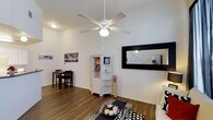 This two-story, 2-bedroom, 2-bathroom home offers a well-organized layout designed for comfortable everyday living. The main living area features hardwood-style flooring that extends throughout, creating a cohesive and easy-to-maintain foundation. A ceiling fan with a light fixture is centrally mounted, providing both airflow and ambient lighting to the space. White walls keep the interior bright and versatile, complementing the clean, neutral aesthetic throughout.

The living room is generously proportioned, with enough space to accommodate a seating area and an adjacent dining nook. A large framed mirror on the wall adds depth to the room while reflecting light and visually expanding the area. A white open shelving unit serves as both a display and storage feature, adding character to the space.

The two-story configuration provides separation between living and sleeping areas, enhancing privacy and functionality. With two full bathrooms and two bedrooms spread across the floors, the layout accommodates a variety of living arrangements. The overall ambiance is clean, bright, and practical, making it a well-suited space for those seeking a straightforward and comfortable home.