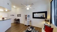 This two-story, 2-bedroom, 2-bathroom home offers a well-organized layout designed for comfortable everyday living. The main living area features hardwood-style flooring that extends throughout, creating a cohesive and easy-to-maintain foundation. A ceiling fan with a light fixture is centrally mounted, providing both airflow and ambient lighting to the space. White walls keep the interior bright and versatile, complementing the clean, neutral aesthetic throughout.

The living room is generously proportioned, with enough space to accommodate a seating area and an adjacent dining nook. A large framed mirror on the wall adds depth to the room while reflecting light and visually expanding the area. A white open shelving unit serves as both a display and storage feature, adding character to the space.

The two-story configuration provides separation between living and sleeping areas, enhancing privacy and functionality. With two full bathrooms and two bedrooms spread across the floors, the layout accommodates a variety of living arrangements. The overall ambiance is clean, bright, and practical, making it a well-suited space for those seeking a straightforward and comfortable home.