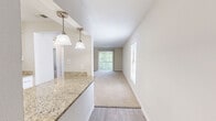 Located in Temple Terrace, Florida, this single-floor, 2-bedroom, 1-bathroom residence offers a well-organized and functional layout. The kitchen is a standout feature, boasting granite countertops, crisp white shaker cabinetry, stainless steel appliances, and elegant pendant lighting — a clean, modern aesthetic that serves as the heart of the home. The living area is carpeted and bathed in natural light, with a sliding glass door fitted with vertical blinds that opens to a lush, tree-lined outdoor view, creating a bright and welcoming atmosphere. The spacious primary bedroom features soft carpeting, a closet, and direct access to the full bathroom, which is appointed with granite countertops, white cabinetry, a tub-shower combination with tile surround, and wood-look flooring. The second bedroom is similarly carpeted and features a window with views of the surrounding greenery, offering a quiet and comfortable retreat. Throughout the residence, neutral tones, clean walls, and consistent finishes create a cohesive and move-in-ready environment. The textured ceilings and ample closet space in the bedrooms add to the practical appeal of this well-maintained home.