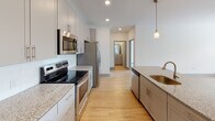 Located at 355 Walnut St in Chattanooga, Tennessee, this well-appointed multi-floor residence offers a clean, modern aesthetic across two levels. The open-concept living and kitchen area is anchored by light hardwood flooring that extends throughout the main living spaces, creating a warm and cohesive feel. The kitchen is thoughtfully designed with granite countertops, gray cabinetry, stainless steel appliances including a range, microwave, refrigerator, and dishwasher, and pendant lighting that adds a refined touch. A kitchen island with a sink provides additional workspace and a natural gathering point. Bedrooms are carpeted for comfort and feature ceiling fans, generous closet space, and windows that frame views of the surrounding Chattanooga neighborhood, including glimpses of classic brick architecture nearby. The bathrooms are finished with crisp white subway tile surrounds in the tub-shower combinations, chrome fixtures, and wood-look flooring, offering a clean and functional design. Throughout the space, recessed lighting, neutral walls, and consistent trim details contribute to a polished, move-in-ready environment. The two-floor layout provides distinct separation between living and private areas, making this a well-structured and versatile residence in the heart of Chattanooga.