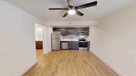 Located at 207 E Mountcastle Dr in Johnson City, Tennessee, this single-floor unit offers a thoughtfully updated interior with a cohesive, modern aesthetic. The open layout connects the living area to a well-equipped kitchen, which serves as a focal point of the space. The kitchen features rich, dark-stained shaker-style cabinetry, white quartz countertops, a subway tile backsplash, and a full suite of stainless steel appliances, including a refrigerator, electric range, over-the-range microwave, and dishwasher. Light hardwood flooring runs consistently throughout the unit, lending warmth and visual continuity to every room. Ceiling fans are installed in the main living area and bedroom, providing both comfort and ambient lighting. The bedroom is generously sized with a closet fitted with panel doors and a built-in hanging rod. A window in the bedroom allows natural light to filter in. The bathroom is clean and functional, offering a tub-shower combination with tiled surround, a vanity with a white countertop and undermount sink, and wood-toned cabinetry. The unit's neutral color palette and updated finishes create a bright, move-in-ready environment well suited for comfortable everyday living.