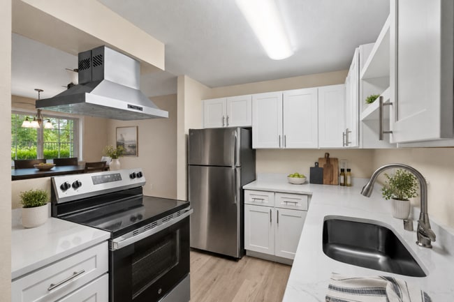 A bright, updated kitchen with modern finishes, generous cabinet storage, stainless steel appliances, and an open view into the dining area. - Crossroads at Meridian Apartments