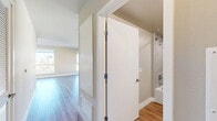 Located at 215 W 14th St in the vibrant South Park neighborhood of Los Angeles, this well-appointed studio offers a thoughtfully designed single-floor layout that maximizes every square foot. The combined kitchen and living area serves as the heart of the unit, featuring warm hardwood-style flooring that flows seamlessly throughout. The modern kitchen is outfitted with crisp white cabinetry, stainless steel appliances including a range, microwave, and dishwasher, complemented by a tasteful tile backsplash and ample counter space. Large windows throughout the living area flood the space with natural light and frame striking views of the downtown Los Angeles skyline, bringing the energy of the city indoors. The bathroom is finished with contemporary touches, including a full soaking tub and shower with large-format grey tile surround, a white vanity with undermount sink, and wood-look flooring. A hallway connects the main living space to the bathroom, two closets offering generous storage, and a dedicated laundry area for added convenience. Neutral wall tones and clean white trim throughout lend the unit a bright, modern aesthetic well-suited to urban living.