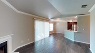 The Cherrywood residence is a thoughtfully designed 2-bedroom, 2-bathroom single-floor home that combines comfort and modern style. The open-concept living and dining area is anchored by dark hardwood-style flooring that runs throughout, creating a warm and cohesive aesthetic. Crown molding adds a refined architectural touch, while large vertical-blind-covered sliding doors invite generous natural light and provide seamless access to the outdoors.

The kitchen is positioned adjacent to the main living space and features rich, dark wood cabinetry, stainless steel appliances, and a light-toned countertop peninsula that doubles as a casual dining or prep surface. Recessed lighting and a decorative pendant light above the peninsula enhance the kitchen's functionality and visual appeal.

A tray ceiling detail in the dining area adds architectural dimension and helps define the space within the open floor plan. The neutral wall tones throughout complement both the flooring and cabinetry, creating a balanced and inviting atmosphere. The textured ceiling finish adds subtle character to the overall design. This residence offers a well-appointed layout ideal for everyday living, with thoughtful details that elevate the space beyond the ordinary.