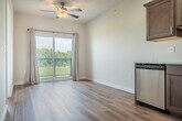 Located at 4185 Timothy Ct in De Forest, Wisconsin, this single-floor unit offers a thoughtfully designed layout that maximizes every square foot. The open kitchen serves as the heart of the space, featuring rich dark-stained cabinetry, light countertops, and a full suite of stainless steel appliances including a range, microwave, dishwasher, and refrigerator. Light wood-tone flooring runs throughout the main living and kitchen areas, adding warmth and continuity to the design. Recessed lighting overhead keeps the kitchen bright and functional.

The spacious primary bedroom is finished with plush carpet, a ceiling fan with light fixture, and a generously sized closet with bifold doors and built-in shelving. A large window frames scenic outdoor views of the surrounding greenery, filling the room with natural light. A baseboard heating unit ensures year-round comfort.

A dedicated laundry room provides added convenience, housing a stacked washer and dryer unit alongside additional shelving. The entryway features a bold dark-paneled door that makes a clean, modern statement against the crisp white walls. Overall, the space presents a clean, contemporary aesthetic with practical finishes suited for everyday living.