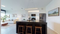 Located on Literary Road in Cleveland's vibrant Ohio City neighborhood, this single-floor unit showcases a clean, modern design aesthetic defined by crisp white walls, light wood-tone flooring, and bold black accents throughout. The open-concept layout connects the kitchen and living areas seamlessly, creating an expansive, cohesive living space ideal for both everyday living and entertaining.

The kitchen is a standout feature, centered around a large dark-countertop island with an undermount sink, pendant lighting, and bar seating for multiple guests. White flat-front cabinetry reaches toward the ceiling with under-cabinet lighting, while stainless steel appliances, including a French door refrigerator, add a polished finish. A linear pendant light fixture overhead reinforces the contemporary design language.

The living area is bright and welcoming, benefiting from large windows that invite natural light and provide outdoor views. Light flooring and neutral furnishings create a calm, airy atmosphere complemented by warm wood-toned accents and lush greenery.

The bedroom features floor-to-ceiling windows, a barn-style sliding door, and generous closet space with an in-unit stacked washer and dryer conveniently nearby. The bathroom offers a glass-enclosed walk-in shower with white tile surround, matte black fixtures, and slate-toned floor tile, balancing modern style with functional design.