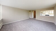 Located at 660 Boas St in Harrisburg, Pennsylvania, this single-floor residence offers a straightforward and functional layout designed for comfortable everyday living. The entry hallway provides immediate access to the main living areas, with a closet nearby for convenient storage.

The living area is generously proportioned, finished with soft gray carpeting and neutral-toned walls that create a calm, understated atmosphere. Large sliding glass doors open to a private balcony, flooding the space with natural light and offering pleasant outdoor views of surrounding greenery. A wall-mounted air conditioning unit and baseboard heating ensure year-round comfort.

The galley-style kitchen features wood-trimmed white cabinetry extending to the ceiling for ample storage, complemented by white appliances including a gas range, refrigerator, and a stainless steel sink. Durable wood-look flooring completes the practical and clean aesthetic.

The bathroom is a notable feature, showcasing a retro-style design with distinctive pink ceramic tile lining the walls and surround of the full soaking tub and shower combination. Chrome fixtures, a grab bar, and a matching pink sink add to the cohesive vintage character of the space.

Overall, this residence presents a well-organized floor plan with classic detailing, natural light, outdoor access, and functional amenities throughout.