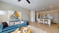 Located in Buckeye, Arizona, this two-bedroom, two-bathroom residence offers a thoughtfully designed single-floor layout with modern finishes throughout. The open-concept living area is bright and welcoming, featuring light wood-style flooring, recessed lighting, and a ceiling fan. Large windows dressed with linen curtains and blinds allow generous natural light to fill the space, creating an airy atmosphere.

The kitchen is well-appointed with light wood cabinetry, stainless steel appliances including a refrigerator, range, and microwave, complemented by a white subway tile backsplash and gray quartz countertops. A central island with bar seating provides a casual dining option and connects seamlessly to the living area.

The primary bedroom features a calming blue accent wall, a ceiling fan, and a window with outdoor views, lending a serene retreat feel. The second bedroom mirrors this comfortable aesthetic. Both bathrooms showcase light wood vanity cabinetry with gray countertops and wood-look tile flooring; one bathroom includes a walk-in glass-enclosed shower, while the other offers a clean, functional layout.

Two hallways connect the space efficiently, and the consistent use of neutral tones and modern hardware throughout creates a cohesive, contemporary ambiance ideal for everyday living.