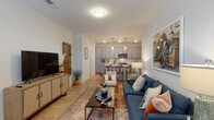 Located at 786 Parker Forest Drive in Dawsonville, Georgia, this single-floor 2-bedroom, 2-bathroom model unit showcases a thoughtfully designed open-concept layout with contemporary finishes throughout. Light wood-style flooring runs seamlessly across the entire residence, contributing to a bright and cohesive aesthetic.

The living area is generously proportioned, featuring large windows that invite natural light and provide a welcoming atmosphere. The space flows directly into the kitchen, which is outfitted with gray shaker-style cabinetry, white quartz countertops, a classic subway tile backsplash, and stainless steel appliances including a range, microwave, and refrigerator. A breakfast bar with pendant lighting offers a casual dining option adjacent to the kitchen.

Both bedrooms are comfortably sized with large windows and ceiling fans. The primary bathroom features a walk-in glass-enclosed shower, dual-sink vanity with gray cabinetry, and wood-look flooring. The second bathroom is equally well-appointed with a full tub-shower combination, single vanity, and matching gray cabinetry.

The entry foyer benefits from a transom window above the front door, filling the space with additional natural light. Throughout, the unit maintains a clean, modern palette of white walls, gray fixtures, and warm wood flooring, creating a balanced and inviting living environment.