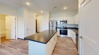 Located at 1810 K St in Lincoln, Nebraska, this well-appointed 3-bedroom, 2-bathroom residence offers a thoughtfully designed single-floor layout. Light wood-style flooring flows consistently throughout, creating a cohesive and clean aesthetic.

The open-concept kitchen, dining, and living area serves as the heart of the home. The kitchen is outfitted with white shaker-style cabinetry, dark countertops, stainless steel appliances including a refrigerator, range, microwave, and dishwasher, and a central island that provides additional workspace and casual seating.

The three bedrooms are bright and well-proportioned, with large windows offering outdoor views and ample natural light. The primary bedroom features a dedicated closet, and abundant storage is available throughout with six closets total across the unit.

Both bathrooms are finished with white vanity cabinetry, dark countertops, and large mirrors. One bathroom includes a shower-tub combination, while both maintain a clean, modern design consistent with the rest of the home.

Additional features include a dedicated laundry room with washer and dryer hookups, a utility room, a hallway connecting the private spaces, an entrance area, and access to a private patio. Recessed lighting and a programmable thermostat add to the home's functional, contemporary character.