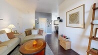 Located at 8445 S Las Vegas Blvd in Las Vegas, NV, this single-floor, one-bedroom, one-bathroom residence offers a practical and comfortable layout. The living room features rich dark hardwood-style flooring, neutral white walls with a contrasting gray accent wall, and warm ambient lighting that creates an inviting atmosphere. Decorative wall shelving adds character and storage. Adjacent to the living area is a dedicated dining space, defined by its clean white walls, dark hardwood-style flooring, and a wall-mounted mirror that adds depth to the room. The galley-style kitchen is equipped with light wood cabinetry, white appliances including a refrigerator, dishwasher, and gas range, ample counter space, and a window that allows natural light to brighten the room. The bedroom features plush carpeting, a ceiling fan with light, a mirrored closet, and a window with outdoor views, providing a restful retreat. Two closets offer convenient storage throughout the unit. The bathroom includes a combination shower and bathtub with sliding glass doors and hardwood-style flooring, maintaining a consistent design aesthetic. Overall, the space presents a cohesive, functional, and comfortable living environment.