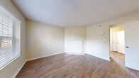 This two-floor residence in Chattanooga, TN (37416) offers a well-organized layout with a blend of practical finishes and comfortable living spaces throughout. The main living area is spacious and open, featuring rich hardwood-style flooring, warm neutral walls, and a textured ceiling. A standout feature of the living room is the tiled fireplace surround, adding character to the space. A large window allows natural light to fill the room, offering views of the surrounding greenery. The kitchen is thoughtfully updated with dark gray cabinetry, granite-style countertops, a mosaic tile backsplash, black appliances including a refrigerator and electric range, and hardwood-style flooring that continues the cohesive aesthetic. The bedrooms are carpeted for comfort and each features a ceiling fan with light fixture and windows that bring in natural light. Closet access and proximity to the bathroom provide added convenience in the bedroom areas. The bathroom includes a full tub-shower combo, a dark-vanity with granite-style countertop, and hardwood-style flooring. Throughout the home, the consistent use of neutral tones and quality finishes creates a clean, move-in-ready atmosphere suitable for everyday living.