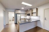 Located at 400 Langley Rd in Newton, MA, this modern 1-bedroom, 2-bathroom residence offers a thoughtfully designed single-floor layout with clean contemporary finishes throughout. The open-concept living, dining, and kitchen area serves as the heart of the home, featuring warm wood-tone flooring that flows seamlessly across the space. The kitchen is well-appointed with stainless steel appliances including a refrigerator, range, microwave, and dishwasher, complemented by light wood cabinetry, a white subway tile backsplash, and a dark-topped island that provides additional prep and dining space. The living area benefits from natural light and direct access to a private balcony, offering outdoor views of the surrounding neighborhood. The spacious primary bedroom includes access to a dedicated closet and connects conveniently to the rest of the unit. Both bathrooms are finished in a modern style; one features a full soaking tub with tiled surround, a wood-toned vanity with dark countertop, and well-lit mirror. The unit includes four closets and in-unit laundry, providing exceptional storage and convenience. Crisp white walls, recessed and flush ceiling lighting, and consistent flooring throughout contribute to a bright, cohesive aesthetic well-suited for comfortable everyday living.