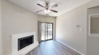 This single-floor, one-bedroom, one-bathroom home at 4447 Rainier St in Irving, TX offers a well-organized layout with a variety of functional spaces. The open-concept living, dining, and kitchen area forms the heart of the home, finished with wood-look luxury vinyl plank flooring throughout. The living room is highlighted by a white-surround fireplace, a ceiling fan with light kit, and a sliding glass door that opens to a private outdoor patio, allowing natural light to flow freely into the space. The kitchen features white cabinetry, black appliances including a range and over-the-range microwave, a stainless steel sink, and a generous peninsula with a light stone-finish countertop — ideal for casual dining or additional prep space. The bedroom is a well-proportioned retreat with a large window fitted with blinds, providing natural light and privacy. The bathroom offers a full soaking tub, white vanity with stone countertop, and hardwood-style flooring. Additional highlights include a dedicated den, a laundry room, three closets, and a hallway connecting the private areas of the home. Textured ceilings are featured throughout, adding a classic finishing touch to the neutral, light-toned interior palette.
