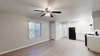 Located at 3135 Comanche Rd NE in Albuquerque, New Mexico, this single-floor unit offers a practical and well-organized layout. Light wood-look flooring runs throughout the space, contributing to a clean, cohesive aesthetic.

The combined kitchen and living area forms the heart of the unit. The kitchen is equipped with white cabinetry, a subway tile backsplash, a gas range, a refrigerator, and a single-basin sink. A textured ceiling with recessed fluorescent lighting keeps the kitchen well-lit. The adjacent living area is an open, neutral-toned space with a ceiling fan and a window fitted with vertical blinds, allowing natural light to filter in and offering a view of the surrounding exterior.

The bathroom is cleanly finished with a white vanity featuring storage cabinetry, a toilet, and a full tub-shower combination with chrome fixtures. Light wood-look flooring continues from the main living area into the bathroom, maintaining design consistency. Neutral wall tones and a well-placed light fixture above the vanity keep the space feeling bright and functional.

Overall, the unit presents a straightforward, low-maintenance interior with consistent finishes, making it a practical option in the Albuquerque area.