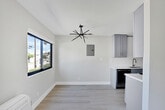 Located at 6958 Woodman Ave in the Van Nuys neighborhood of Los Angeles, this thoughtfully renovated single-floor unit showcases a clean, modern aesthetic carried consistently throughout every room. Light wood-tone flooring runs seamlessly across the entire space, complementing the bright white walls and creating an airy, open atmosphere.

The kitchen is a standout feature, equipped with stainless steel appliances including a full-size refrigerator, range with oven, and over-the-range microwave. Gray shaker-style cabinetry with gold hardware pairs elegantly with quartz countertops and a classic white subway tile backsplash. A deep stainless steel undermount sink with a gold-finish pull-down faucet adds a refined touch.

The living areas are generously proportioned, filled with natural light from large windows that frame views of the surrounding neighborhood. The bedrooms offer well-sized closets, including a mirrored sliding-door closet, and wall-mounted heating units for individual climate control. Recessed lighting adds a polished finish to the main living spaces.

The bathroom continues the modern design language with white subway tile lining the tub surround, quartz countertops, gray cabinetry with matte black hardware, and a window above the tub for added ventilation and natural light. The overall design is cohesive, minimal, and move-in ready.