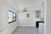 Located at 6958 Woodman Ave in the Van Nuys neighborhood of Los Angeles, this thoughtfully renovated single-floor unit showcases a clean, modern aesthetic carried consistently throughout every room. Light wood-tone flooring runs seamlessly across the entire space, complementing the bright white walls and creating an airy, open atmosphere.

The kitchen is a standout feature, equipped with stainless steel appliances including a full-size refrigerator, range with oven, and over-the-range microwave. Gray shaker-style cabinetry with gold hardware pairs elegantly with quartz countertops and a classic white subway tile backsplash. A deep stainless steel undermount sink with a gold-finish pull-down faucet adds a refined touch.

The living areas are generously proportioned, filled with natural light from large windows that frame views of the surrounding neighborhood. The bedrooms offer well-sized closets, including a mirrored sliding-door closet, and wall-mounted heating units for individual climate control. Recessed lighting adds a polished finish to the main living spaces.

The bathroom continues the modern design language with white subway tile lining the tub surround, quartz countertops, gray cabinetry with matte black hardware, and a window above the tub for added ventilation and natural light. The overall design is cohesive, minimal, and move-in ready.