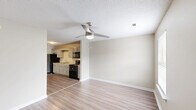 Located at 304 Fort Town Dr in Fort Oglethorpe, GA, this single-story unit offers a practical and comfortable layout across one floor. The open-concept kitchen and living area forms the heart of the home, featuring wood-look plank flooring, a textured ceiling, and a ceiling fan that enhances airflow throughout the space. The kitchen is outfitted with gray cabinetry, white countertops, a double-basin stainless steel sink, and black appliances including a refrigerator, electric range, and over-the-range microwave. Ample cabinet storage lines the walls, providing generous organization options. The living area flows naturally from the kitchen, brightened by a window that invites natural light. The bedroom is a well-proportioned retreat finished with plush carpeting, a ceiling fan with light fixture, a window with blinds offering outdoor views, and a closet for storage. The full bathroom features a single-sink vanity with gray cabinetry, a lighted mirror, and a tub-shower combination. A dedicated utility room rounds out the layout, adding functional storage and laundry space. Neutral tones and clean finishes throughout give the unit a bright, move-in-ready feel.