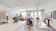 This thoughtfully designed single-floor residence offers a seamless blend of comfort and modern style throughout its open, airy layout. The heart of the home is the open-concept living and dining area, where wide-plank wood-look flooring, a ceiling fan, and an abundance of natural light from multiple windows create a warm and inviting atmosphere. French doors lead directly to a private balcony, extending the living space outdoors with pleasant surrounding views.

The kitchen is a functional centerpiece, featuring rich dark-stained cabinetry, light quartz countertops, stainless steel appliances, a subway tile backsplash, and a central island with seating for two — ideal for casual dining or entertaining. Pendant lighting adds a refined touch overhead.

The dining area sits adjacent to the living space, bathed in natural light from large windows dressed with classic plantation shutters and sheer curtains. The bedrooms offer plush carpeting and generous windows that invite natural light, while the primary suite includes access to a walk-in closet with multi-level shelving and hanging rods. The bathrooms are clean and well-appointed, with one featuring a tiled walk-in shower and another with a full soaking tub and shower combo, both complemented by wood-toned vanities and crisp white finishes throughout.