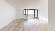 Located at 340 Colborne in London, Ontario, this well-appointed one-bedroom, one-bathroom unit offers a thoughtfully designed layout across a single floor. Luxury vinyl plank flooring flows throughout the space, complementing the clean, bright aesthetic created by crisp white walls and textured ceilings.

The living and dining area is a standout feature, anchored by an impressive floor-to-ceiling wraparound window wall that floods the space with abundant natural light and offers expansive panoramic views of the surrounding cityscape and skyline. A private balcony extends from this area, providing an outdoor retreat. Baseboard heating runs along the perimeter, ensuring year-round comfort.

The galley-style kitchen is efficiently designed with white cabinetry, gold-tone hardware, grey subway tile backsplash, and stainless steel appliances including a refrigerator, stove, microwave, and dishwasher, all paired with a double sink.

The well-sized bedroom features a built-in closet with panel doors and access to additional storage. Three closets in total provide generous storage throughout the unit. The bathroom is finished with large-format grey tile surrounding a full soaker tub and shower. A dedicated in-unit laundry room with a stacked washer and dryer adds everyday convenience. The entrance and hallway complete this functional, modern home.