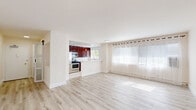 Located on the prestigious Wilshire Boulevard corridor in Los Angeles, this 2-bedroom, 2-bathroom residence offers a thoughtfully designed single-floor layout with clean, modern finishes throughout. Light-toned hardwood-style flooring runs continuously across the space, complementing the bright white walls and creating a cohesive, airy ambiance. The entry features a sleek frosted-glass sliding barn door, adding a stylish architectural touch. The open living area is bathed in natural light from large windows dressed with sheer white curtains, seamlessly connecting to the kitchen. The kitchen stands out with rich mahogany cabinetry, light quartz countertops, a breakfast bar peninsula, stainless steel appliances, and pendant lighting. The spacious primary bedroom includes mirrored sliding closet doors that amplify light, along with natural views through large windows. The second bedroom is equally well-lit and comfortable. Four closets provide generous storage throughout. Both bathrooms are finished in crisp white tile — one featuring a glass-enclosed walk-in shower, the other a combination shower and tub with a sliding glass door. A dedicated in-unit laundry area adds everyday convenience. With four closets and a bright, open feel, this residence offers functional elegance in a prime Los Angeles location.