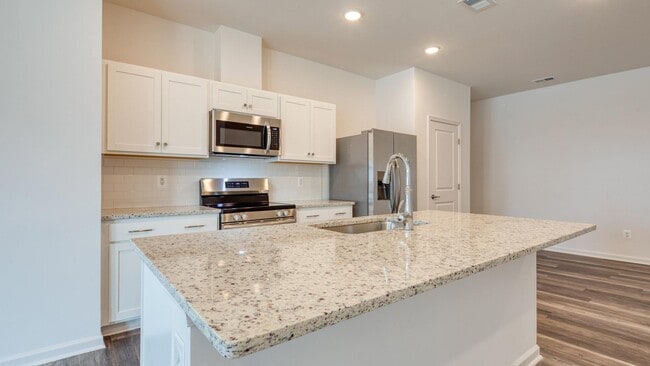 Island kitchen with quartz countertops. - The Mark Townhomes