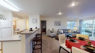 Located at 13107 East Mission Avenue in Spokane, WA, Unit 30 is a well-appointed single-floor residence designed for comfortable, everyday living. The entry hallway welcomes you with neutral carpet flooring and warm wood-toned doors, with access to a closet for convenient storage.

The open-concept living and dining area is a central highlight, featuring plush carpet and generous natural light from large windows that frame outdoor views of the surrounding neighborhood. A sliding glass door leads directly to a private balcony, further enhancing the connection to the outdoors. A peninsula counter with bar-height seating seamlessly connects the living space to the kitchen.

The kitchen is equipped with ample white cabinetry trimmed in warm wood tones, a continuous countertop offering substantial prep space, and a white range. Light wood-style flooring gives the kitchen a clean, practical feel.

Two bedrooms provide comfortable retreats, each carpeted and fitted with windows that bring in natural light and outdoor views. One bedroom features a bold accent wall, while both offer closet storage and a calm, restful atmosphere.

The full bathroom includes a vanity with countertop storage, a large mirror, and a soaking tub with shower combination, finished with tile flooring and neutral-toned wall surrounds for a cohesive look throughout.
