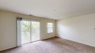 This two-bedroom, one-bathroom residence in Woodstock, Illinois offers a well-organized single-floor layout with a comfortable and functional design throughout. The living room serves as the heart of the home, featuring plush carpeting, neutral cream-toned walls, and large sliding glass doors that open to a private balcony overlooking lush greenery — filling the space with natural light and pleasant outdoor views. An additional window further brightens the room, creating an airy and welcoming ambiance.

The galley-style kitchen is efficiently designed with white cabinetry, white appliances including a gas range, built-in microwave, refrigerator, and dishwasher, complemented by light tile flooring and a double stainless steel sink — providing ample functionality for everyday cooking.

Both bedrooms are carpeted and finished with the same warm, neutral palette. The primary bedroom offers a generous footprint with a built-in closet featuring bifold doors, while the second bedroom benefits from a large window with views of the surrounding landscape. A dedicated closet provides additional storage for the unit.

The bathroom is finished with tile flooring and includes a full-size soaking tub and shower combination with chrome fixtures and a grab bar. A hardwood-floored entryway completes this practical and comfortable residence.