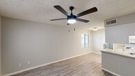 This well-designed one-bedroom, one-bathroom unit is laid out across a single floor, offering a functional and comfortable living experience. The open-concept living room and kitchen area serves as the heart of the home, featuring durable wood-look plank flooring, neutral gray walls, and a textured ceiling fitted with a stylish five-blade ceiling fan with integrated lighting. A window with blinds fills the space with natural light and provides views of the surrounding greenery.

The galley-style kitchen is efficiently arranged with ample white cabinetry on both sides, light stone-look countertops, white appliances including an electric range, microwave, and refrigerator, and a stainless steel sink — all finished with light wood-look flooring for a cohesive aesthetic.

The bedroom offers a comfortable retreat with soft carpeting, neutral walls, a textured ceiling, and a wide three-panel sliding closet that maximizes storage. A ceiling vent ensures effective climate control throughout the room.

The bathroom features a wide vanity with white cabinetry and multiple drawers, a light stone countertop with an integrated sink, a large mirror, and a modern multi-bulb light fixture, creating a bright and clean environment. Wood-look flooring completes the polished look of this thoughtfully designed space.