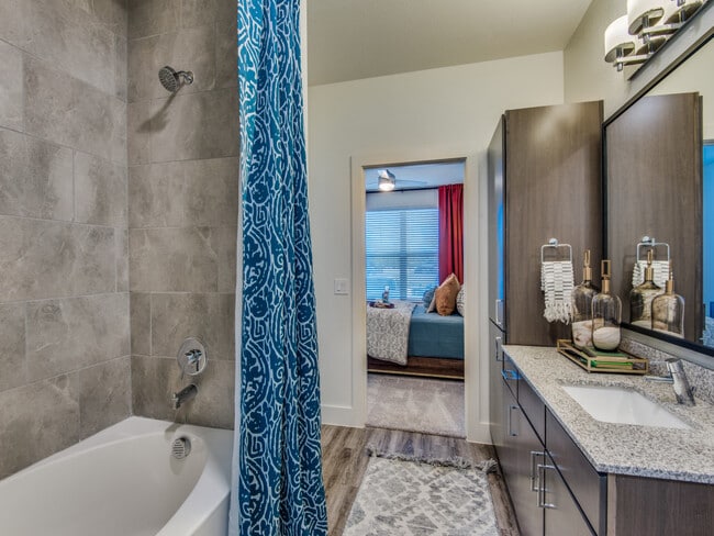 Baño con gabinetes color espresso, encimeras de granito moteado y pisos de superficie dura. - Avalon Castle Hills