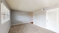 Located at 1315 Morreene Rd in Durham, NC, this one-bedroom, one-bathroom unit offers an efficient single-floor layout designed to maximize every square foot. The living space features neutral gray walls and clean white trim throughout, creating a cohesive and understated aesthetic.

The bedroom is a generously sized room finished with plush wall-to-wall carpeting and a window fitted with blinds that allows natural light to filter in while maintaining privacy. A closet with louvered doors provides practical storage, and the room offers direct visibility into the kitchen and laundry area through an open doorway.

The kitchen is outfitted with hardwood-style flooring and includes a stainless refrigerator and range, alongside white cabinetry. A stacked washer and dryer unit is conveniently integrated into the kitchen area, adding in-unit laundry functionality.

The bathroom features a white vanity with storage drawers, a single-basin sink with chrome fixtures, and a large mirror above the sink that enhances the sense of space.

A standout feature of this unit is the balcony, accessible through a decorative wrought iron screen door, which offers open views of the surrounding neighborhood, mature trees, and parking area. This outdoor space adds a pleasant extension to the interior living experience.