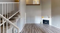 Located at 1901 East Amar Road in West Covina, CA, this two-story, 3-bedroom, 1-bathroom home offers a well-organized layout spread across two floors. The main level immediately impresses with dramatic vaulted ceilings that lend an expansive, airy feel to the living area. Modern gray-toned luxury vinyl plank flooring flows throughout the ground floor, complementing the neutral gray walls. A classic fireplace anchors the living room, while large sliding glass doors open to the patio, inviting abundant natural light and outdoor access. The kitchen is conveniently adjacent to the living area and features white cabinetry and stainless steel appliances. Upstairs, the three bedrooms are carpeted for comfort and each features windows with vertical blinds, providing natural light and ventilation. The primary bedroom includes a closet, while additional closet space is available on the upper floor. The full bathroom is finished with wood-look LVP flooring, a granite-topped vanity, and a tub-shower combination. A hallway connects the upper-level rooms, and a carpeted staircase with a white railing links both floors. The patio provides an outdoor retreat, completing this functional and well-appointed home.