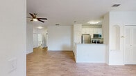 Located in Lady Lake, Florida, this single-story 2-bedroom, 1-bathroom home offers a thoughtfully designed layout with a clean, neutral palette throughout. The entryway welcomes you with tile flooring that transitions into warm wood-look laminate across the open-plan living and dining areas. The living room is bright and airy, featuring a ceiling fan and a sliding glass door that opens to an outdoor view, filling the space with natural light. An arched detail and pendant lighting add character to the dining area, which is lined with windows overlooking the surrounding greenery. The kitchen is well-equipped with granite countertops, white upper cabinetry, gray lower cabinets, a stainless steel refrigerator, microwave, range, and dishwasher, all complemented by tile flooring and a window above the sink. The generously sized primary bedroom features plush carpeting, a ceiling fan, and convenient access to two closets and the full bathroom. The second bedroom also offers carpet flooring and a bright window with natural views. The shared bathroom includes a soaking tub with a tiled shower surround, a vanity with granite countertops, white cabinetry, and tile flooring, completing this comfortable and functional home.