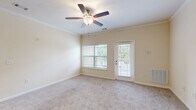 This well-appointed 2-bedroom, 2-bathroom home in Duncan, SC offers a thoughtfully designed single-floor layout that maximizes both comfort and functionality. The open-concept living and kitchen area serves as the heart of the home, where warm wood-look flooring transitions seamlessly from the kitchen into the carpeted living room. The kitchen features a peninsula with a dark granite-style countertop, warm wood cabinetry, track lighting, and black appliances, making it ideal for both everyday cooking and casual entertaining. The living room is bright and inviting, enhanced by crown molding, a ceiling fan, and a glass door leading to a private balcony with outdoor views. Both bedrooms are generously sized with plush carpet flooring and natural light from large windows. The spacious primary bedroom includes a walk-in closet outfitted with multi-tier wire shelving for ample storage. The second bedroom also features its own well-organized closet. The bathrooms are clean and functional, with one featuring a soaking tub and tiled surround. A dedicated laundry room with washer and dryer hookups and overhead shelving adds everyday convenience. Throughout the home, neutral tones and consistent finishes create a cohesive, comfortable ambiance.