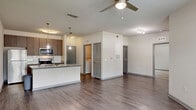 Located at 2509 Cattlemen Rd in Sarasota, FL, this well-appointed one-bedroom, two-bathroom unit offers an efficient and thoughtfully designed single-floor layout. The open-concept living area seamlessly connects the kitchen, dining, and living spaces, creating a bright and functional environment. The kitchen is a standout feature, equipped with stainless steel appliances including a refrigerator, electric range, and microwave, complemented by granite countertops, dark wood cabinetry, a subway tile backsplash, and a center island with a stainless steel sink and pendant lighting overhead. Hardwood-style flooring runs throughout the main living areas, adding warmth and continuity. A ceiling fan anchors the living area, which benefits from natural light through multiple windows offering outdoor views. The bedroom is comfortably sized and carpeted, with windows that invite natural light and a ceiling fan for comfort. Two closets provide ample storage. Both bathrooms feature granite vanity tops and dark wood cabinetry consistent with the overall design aesthetic. A dedicated laundry room houses a full-size washer and dryer. The unit also includes a private patio, extending the living space outdoors — a welcome feature in Sarasota's warm Florida climate.